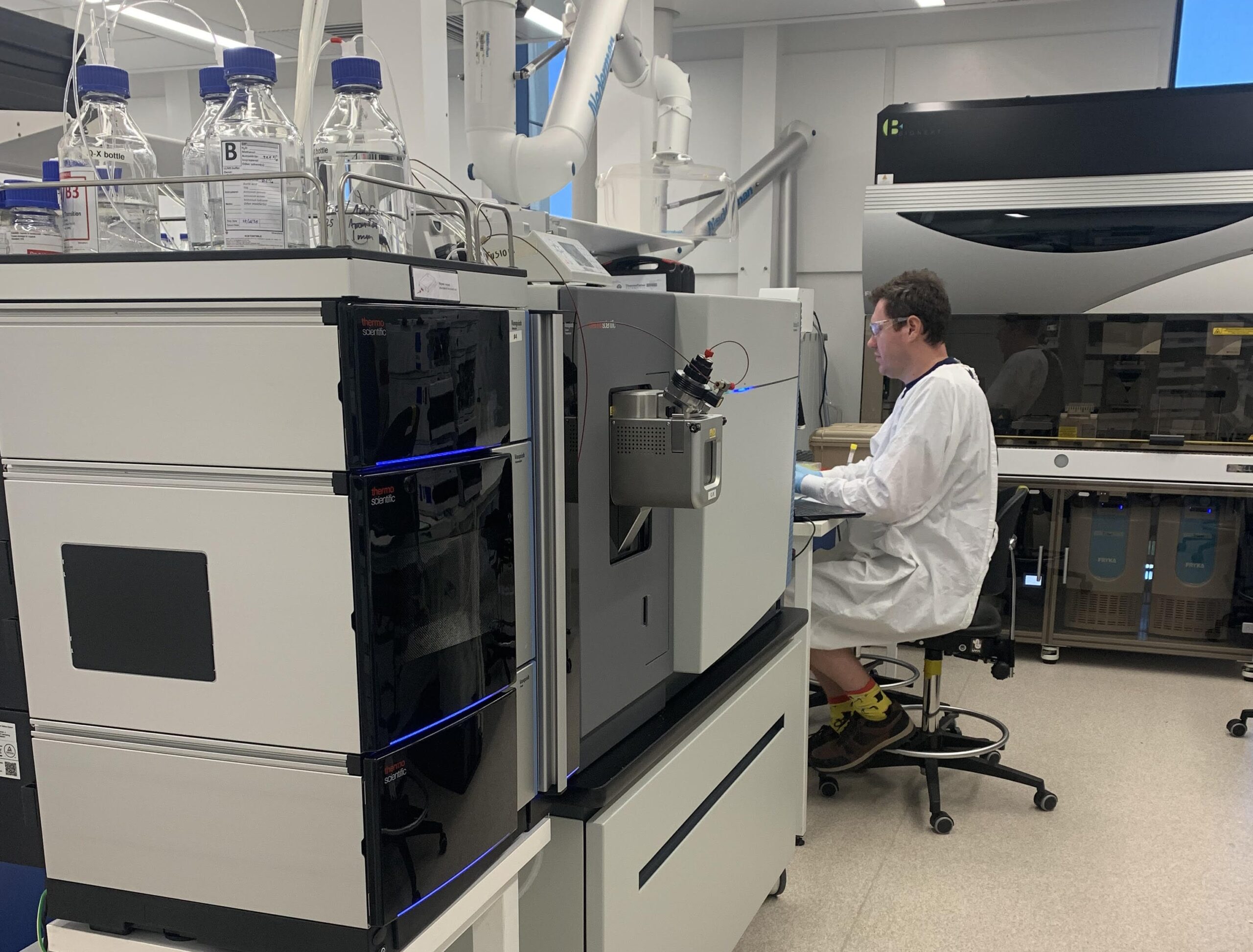 A researcher working beside liquid chromatography and mass spectrometry equipment in the laboratory.